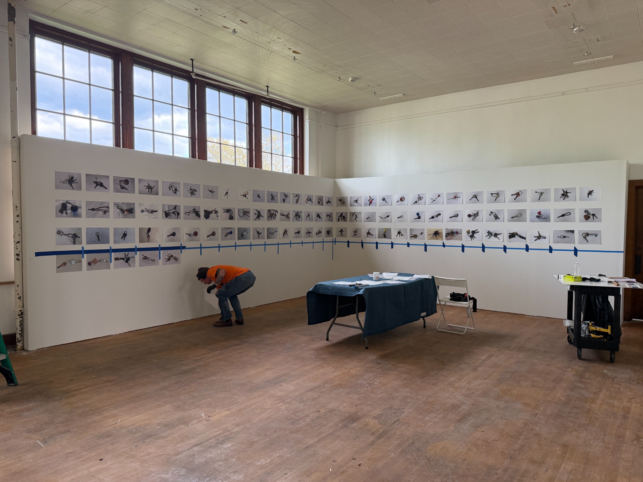 Installer working beneath a wall of photographs at the former Medina High School